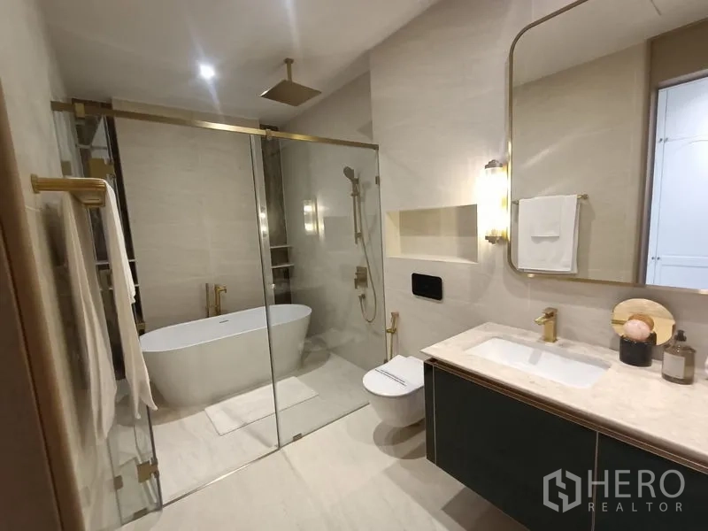Detached House for sale - Modern bathroom with glass shower, freestanding tub and marble vanity with brass fixtures.