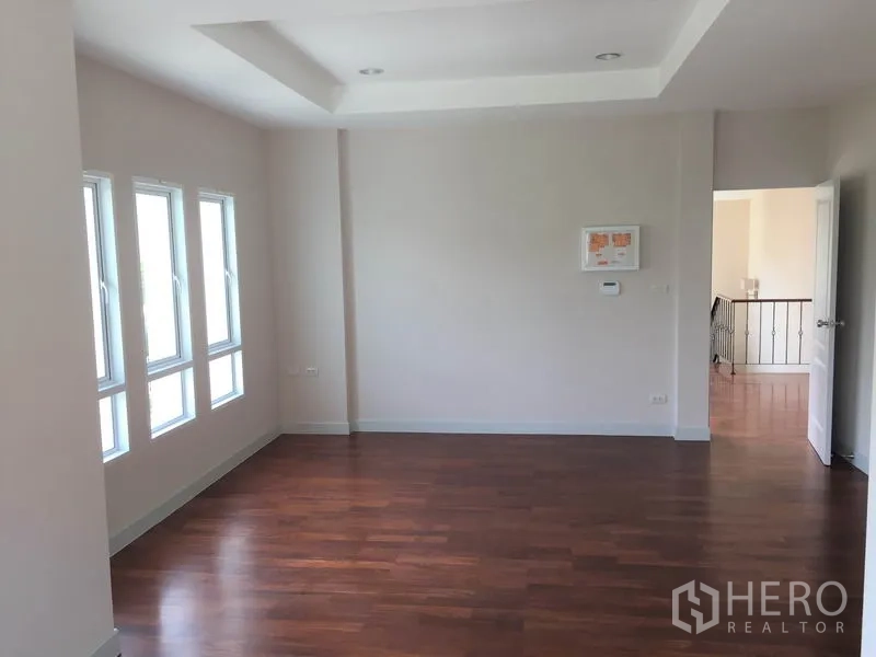 Detached House for rent in Saphan Sung, Bangkok - Spacious bedroom with multiple narrow windows, recessed ceiling and timber flooring.