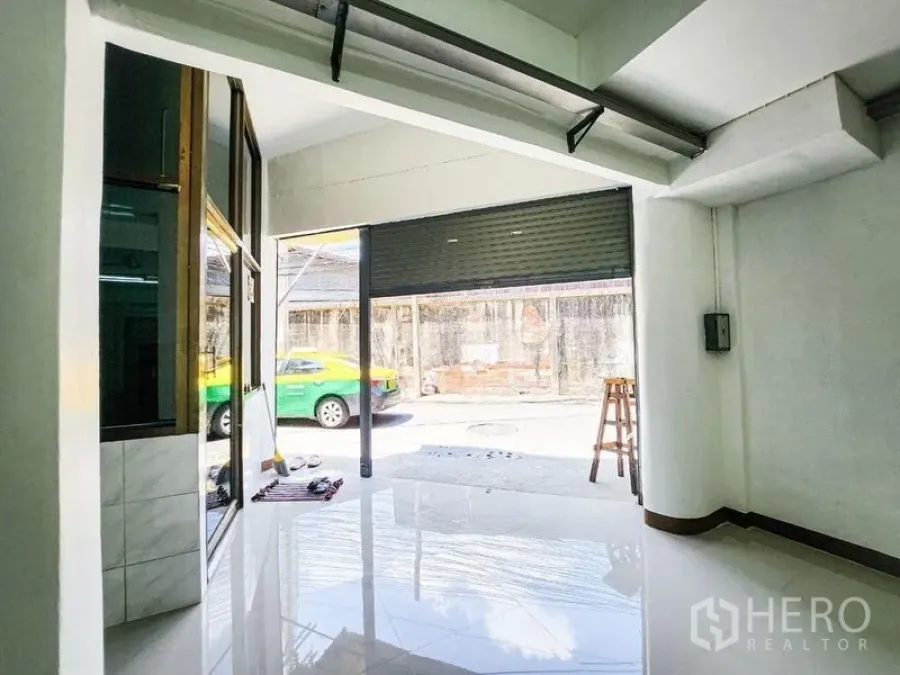 Home Office for rent in Khlong Toei, Bangkok - Street-facing roller shutter entrance and glass frontage viewed from inside.