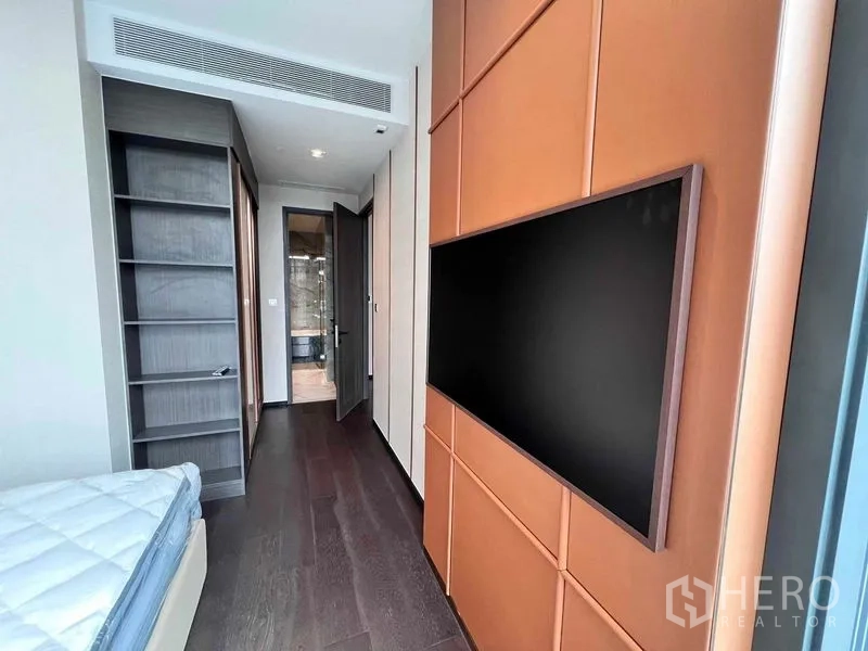 Condominium for rent in Watthana, Bangkok - Bedroom corridor with wall-mounted TV, open shelving, and wood flooring.