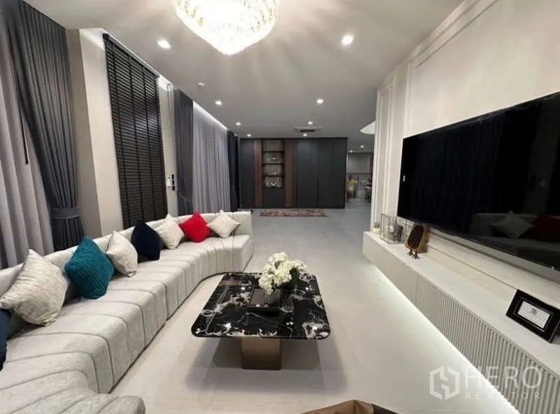 独立式住宅 出租在Lat Krabang, Bangkok - 客厅，超长转角沙发、大理石茶几与壁挂电视。