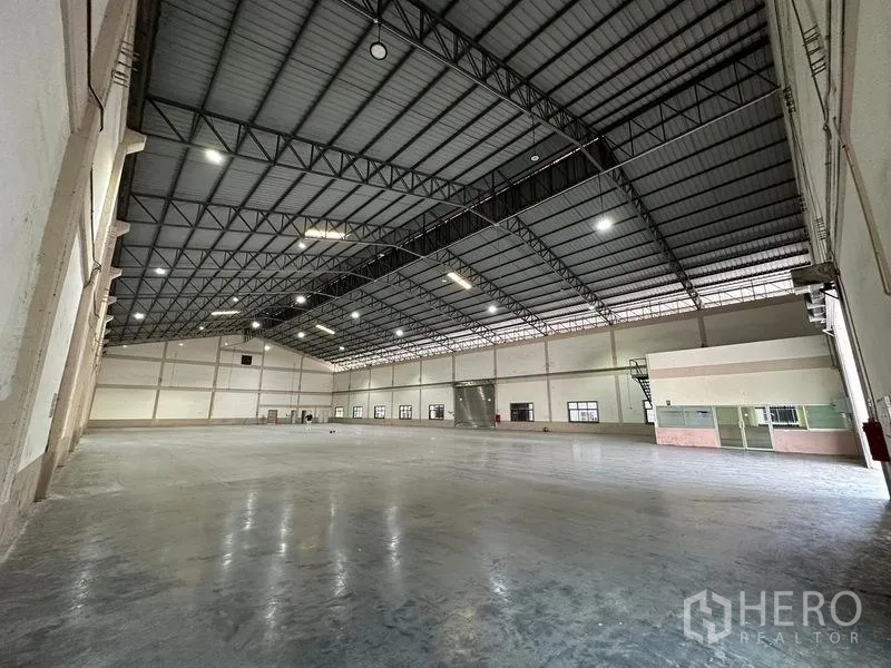 Warehouse for rent in Bang Sao Thong, Samut Prakan - Warehouse interior showing a glass-partitioned office corner and high-bay lights.
