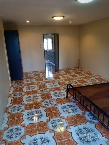 Townhouse for rent in Phra Khanong, Bangkok - Large upstairs bedroom with patterned tiles and a metal bed frame.