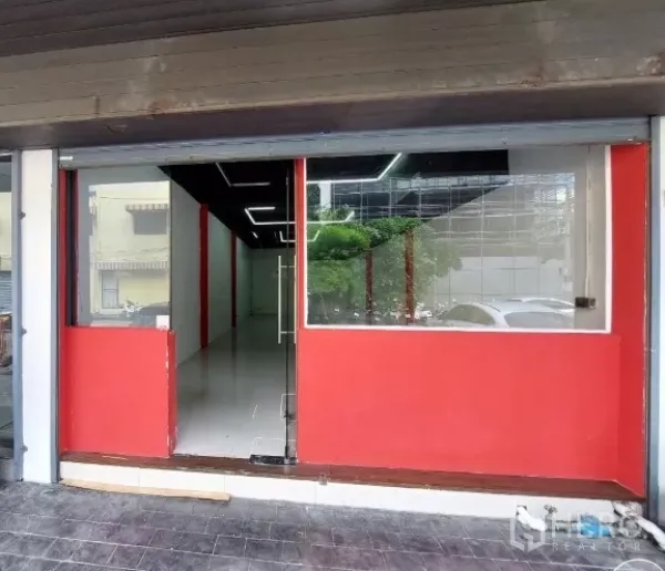 Retail Space for rent in Khlong Toei, Bangkok - Street-level retail frontage with large glass display windows, red panels and a clear glass door.