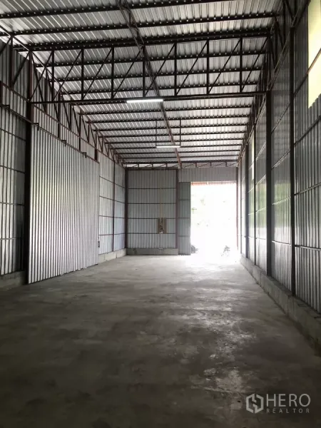 Warehouse for rent in Bueng Kum, Bangkok - Spacious warehouse interior showing a wide sliding metal door and natural light from the open entrance.