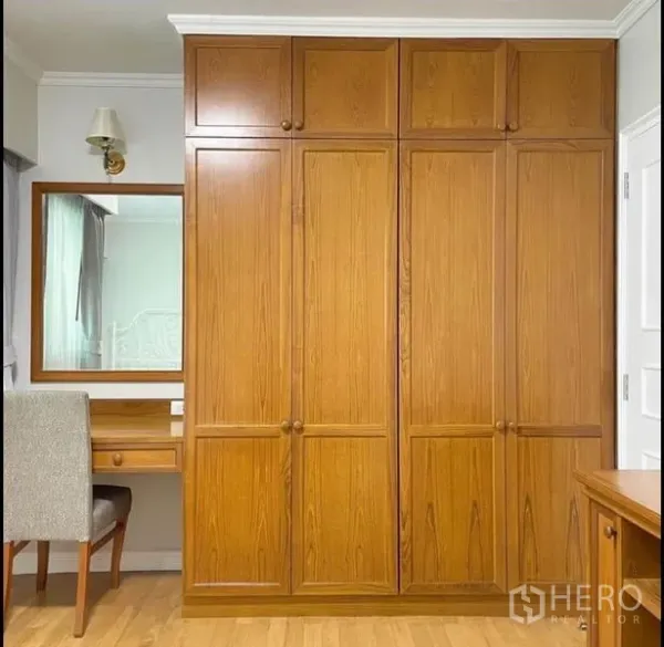 Condominium for rent in Sathon, Bangkok - Bedroom wall with built-in wooden wardrobes and a dressing table.