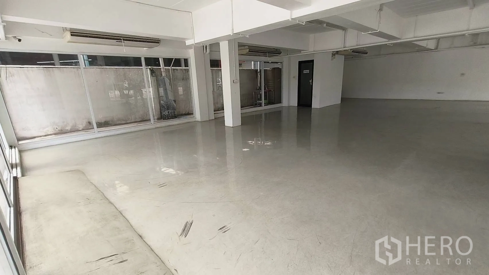 办公空间 出租在Khlong Toei, Bangkok - 展示厅式开放空间，落地窗和柱子。