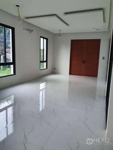 Detached House for rent in Phra Khanong, Bangkok - Sunlit room with white marble tiles and double wooden doors.