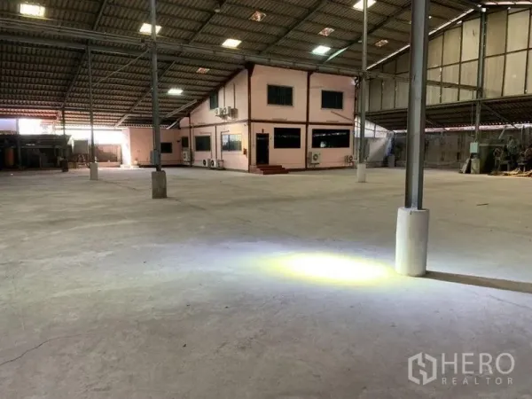 Warehouse for rent - Open floor area with task lights and a fire extinguisher near steel columns.