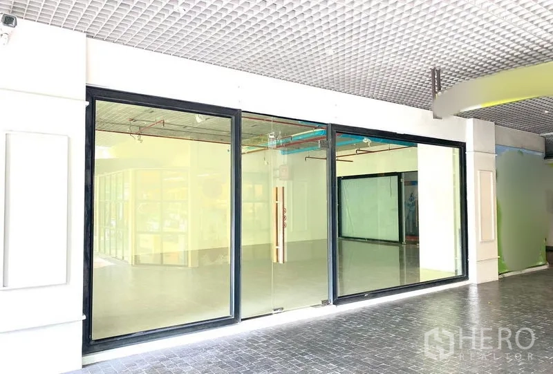 零售空间 出租在Khlong Toei, Bangkok - 黑框大面积玻璃店面，宽幅玻璃入口，位于室内通道。