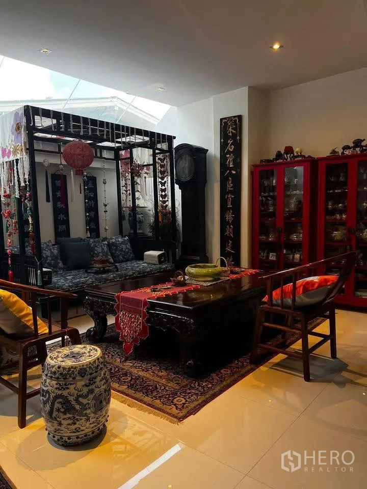 联排别墅 for rent or sale in Watthana, Bangkok - 客厅配中式木质家具、天窗与展示柜。