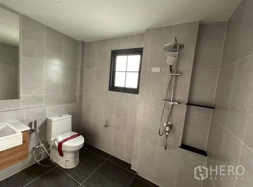 Detached House for rent in Bang Phli, Samut Prakan - Contemporary bathroom with walk-in shower, toilet, gray tiles and window.