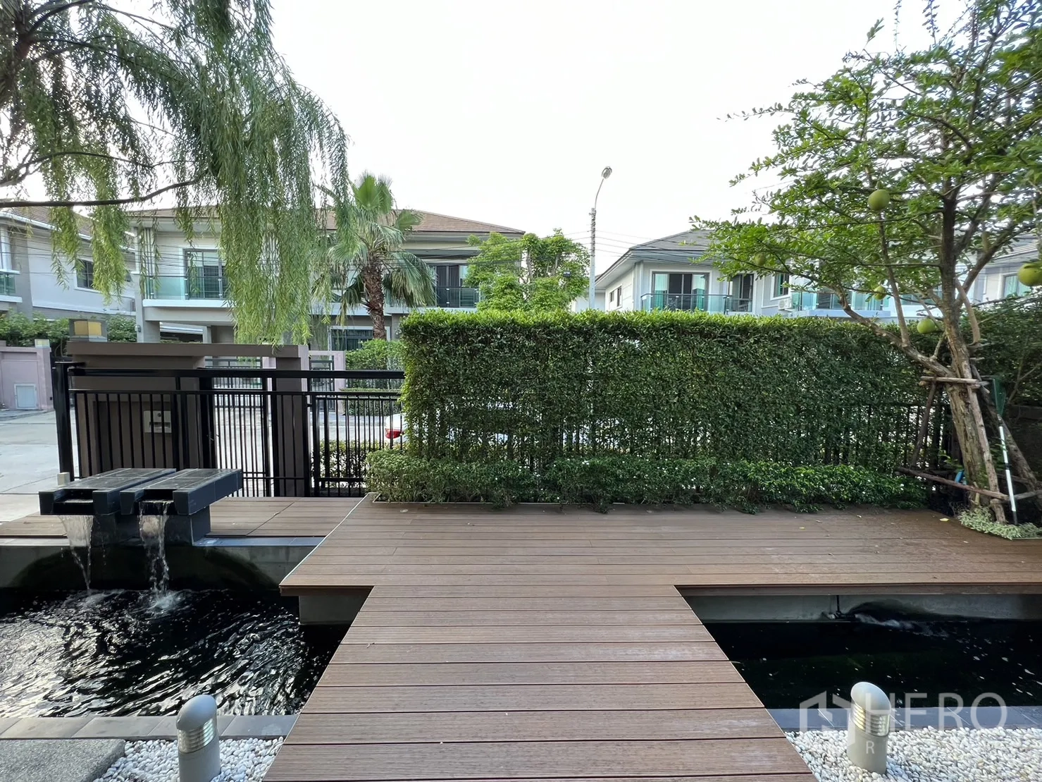 บ้าน ให้เช่าในSuan Luang, Bangkok - ลานหน้าแบบพื้นไม้พร้อมน้ำตกตกแต่ง มองออกไปยังถนนหลังแนวรั้วไม้พุ่ม
