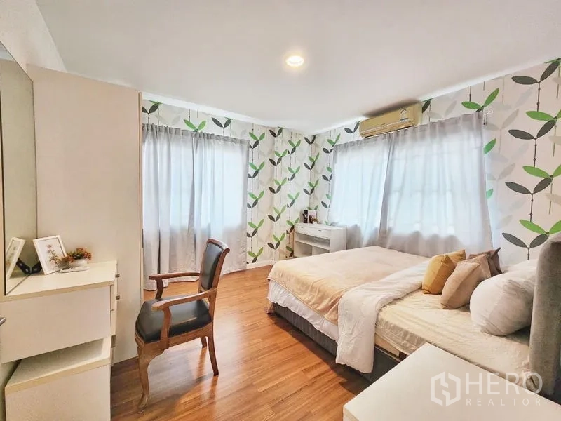 独立式住宅 出租在Prawet, Bangkok - 大次卧，叶纹壁纸、转角窗与座椅。