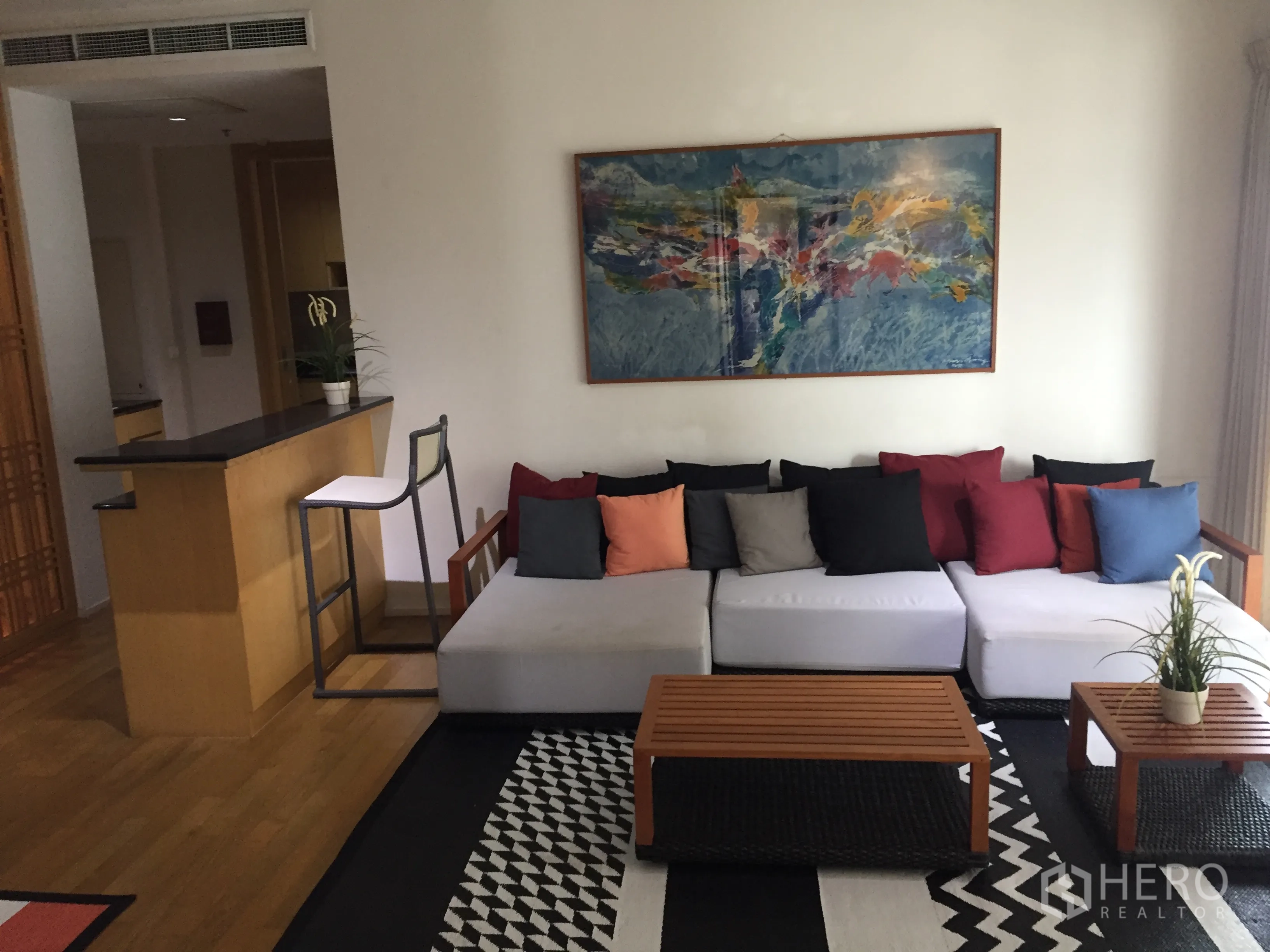 公寓 出租在Watthana, Bangkok - 明亮客厅，超长沙发、吧台与墙面装饰画。