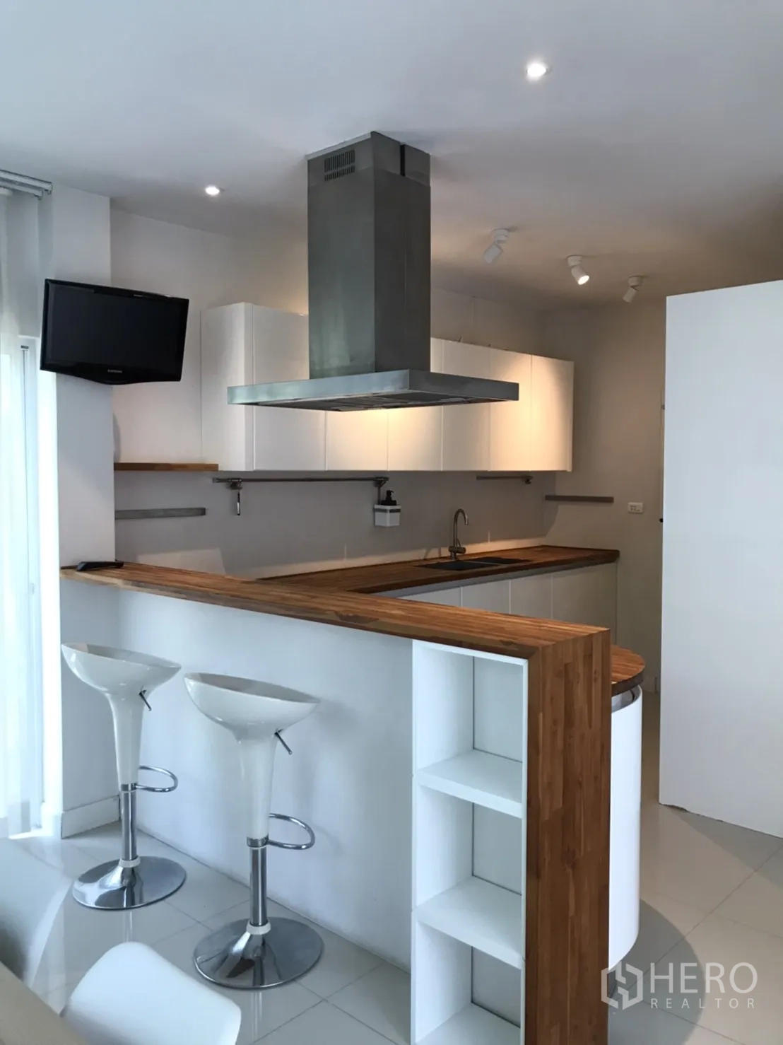 Detached House for rent or sale in Saphan Sung, Bangkok - Modern kitchen with breakfast bar, island hood and two white bar stools.