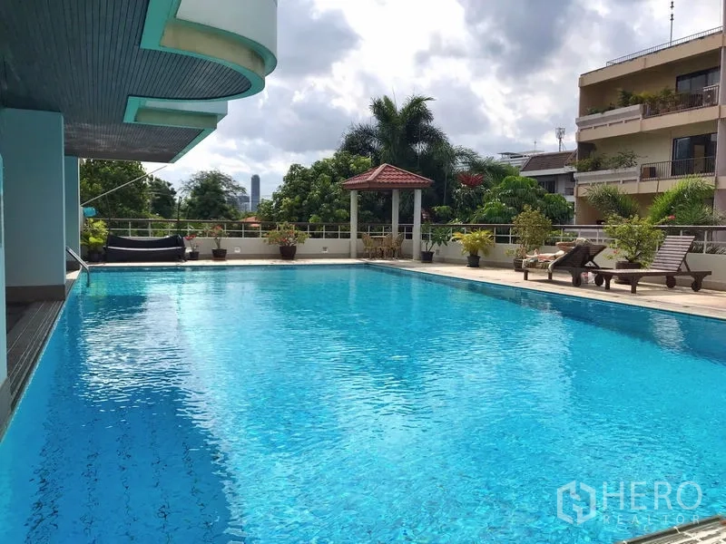 Condominium for rent in Khlong Toei, Bangkok - Large outdoor swimming pool with sun loungers and tropical plants around the deck.