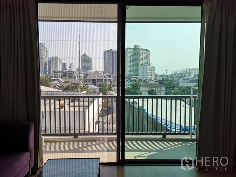 公寓 出售在Watthana, Bangkok - 推拉玻璃门通向阳台，金属栏杆与城市景观