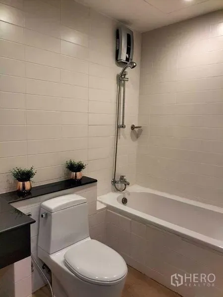 Condominium for rent in Watthana, Bangkok - Second bathroom with bathtub, shower and clean white tiled walls.
