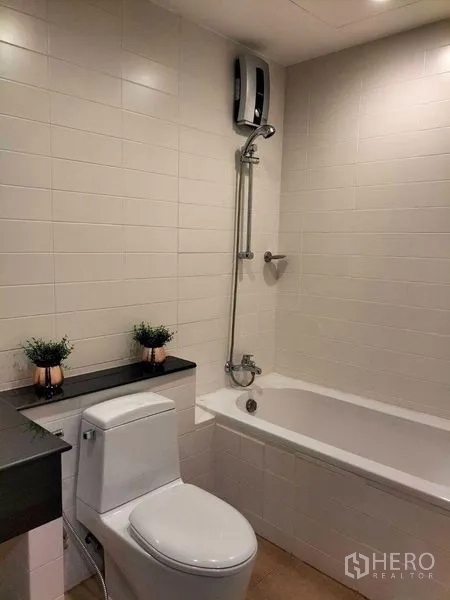 Condominium for rent in Watthana, Bangkok - Second bathroom with bathtub, shower and clean white tiled walls.