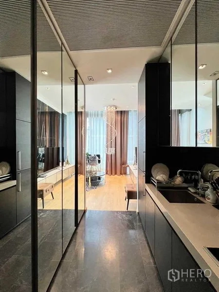 Condominium for rent - Sleek galley kitchen with mirrored cabinetry, sink and stone countertop facing the lounge.