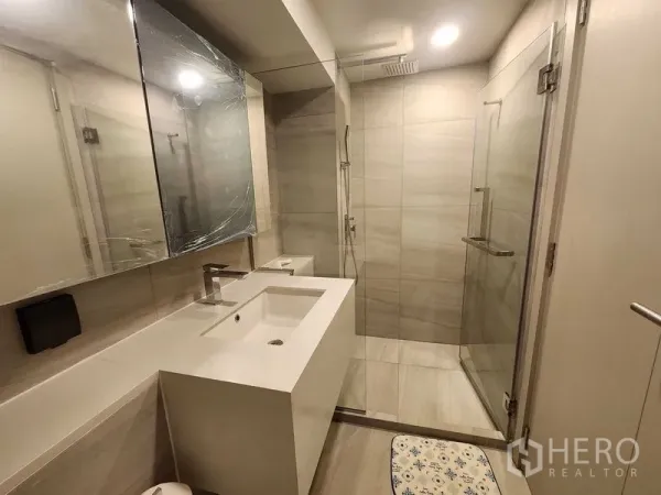 Condominium for rent - Contemporary bathroom with glass shower enclosure, large vanity and warm lighting.