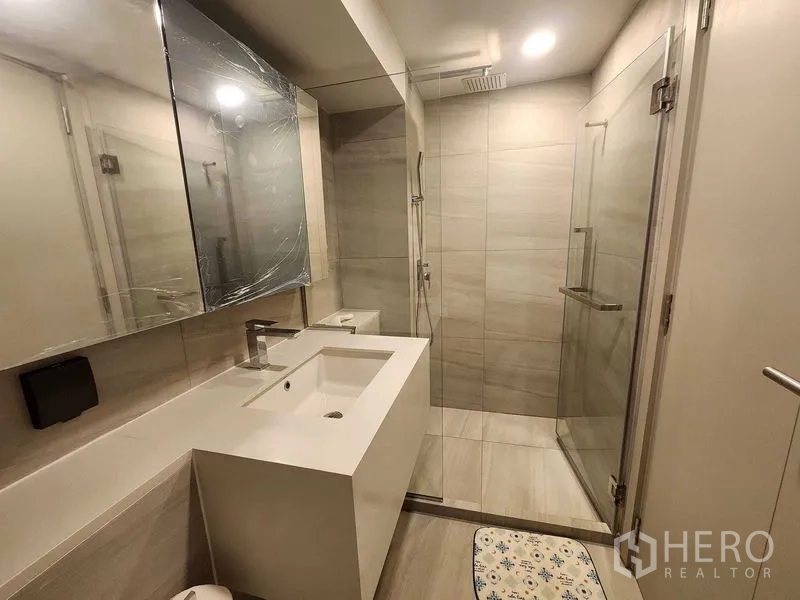 Condominium for rent - Contemporary bathroom with glass shower enclosure, large vanity and warm lighting.