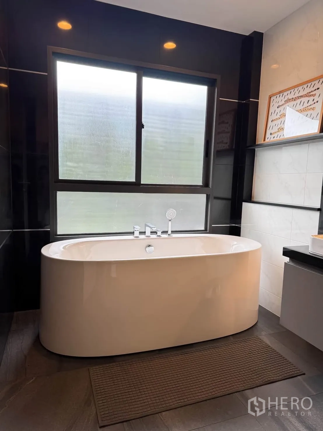 Detached House for rent in Bang Kapi, Bangkok - Bathroom with freestanding oval bathtub by a frosted window and dark tiles.