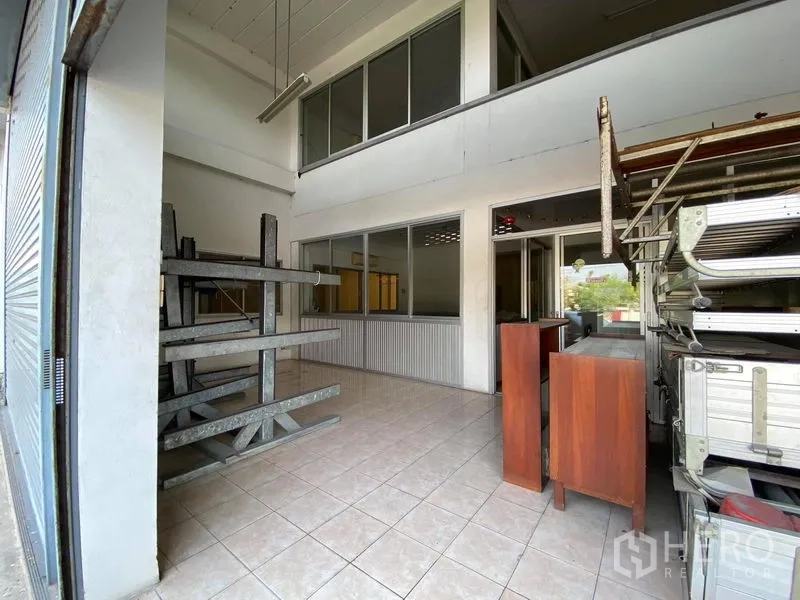 Factory for sale in Bang Phli, Samut Prakan - Loading area behind rolling shutter with mezzanine-style office windows and storage racks.