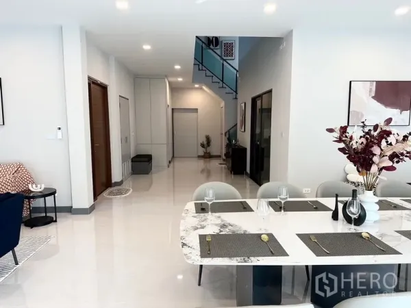 Detached House for rent or sale in Bang Phli, Samut Prakan - Open-plan dining and hallway with marble table and modern staircase.