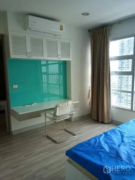 公寓 出租在Ratchathewi, Bangkok - 卧室内置书桌，青绿色玻璃挡板、空调与城市景观窗。