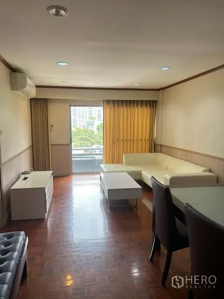 Condominium for rent in Watthana, Bangkok - Bright living room with L-shaped sofa, coffee table and balcony view in a Sukhumvit condo.