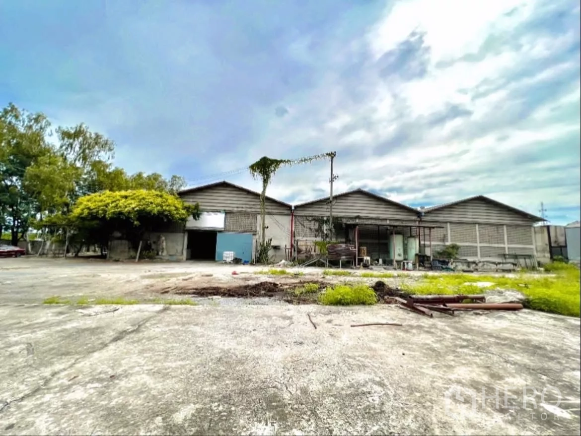 Factory for rent in Sai Noi, Nonthaburi - Front elevation of factory buildings facing an open loading yard with greenery.