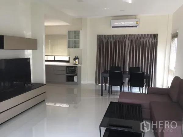 Townhouse for rent or sale in Saphan Sung, Bangkok - Open-plan lounge with dining set and compact kitchen, glossy floors and air conditioning.