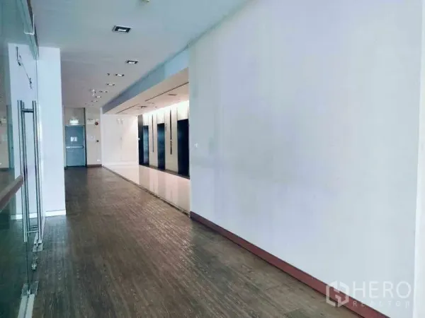 办公空间 出租在Sathon, Bangkok - 明亮走廊与电梯大堂，木纹地面与玻璃隔断。