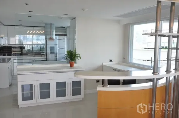 Condominium for rent in Khlong Toei, Bangkok - Contemporary kitchen with white cabinetry, breakfast bar, mirrored backsplash and window views.