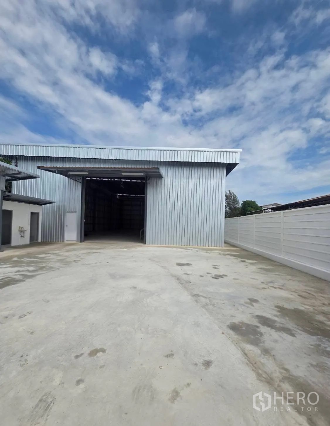 Factory for rent in Mueang Samut Prakan, Samut Prakan - Metal-clad factory exterior with wide roller door and spacious concrete yard.