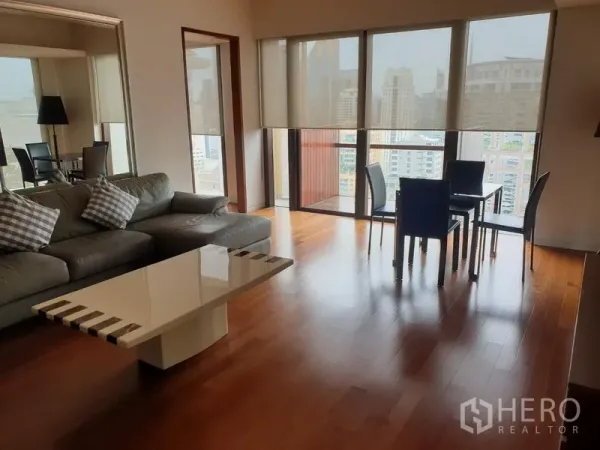 Condominium for rent in Pathum Wan, Bangkok - Bright living and dining area with floor-to-ceiling windows, city views and hardwood floors.
