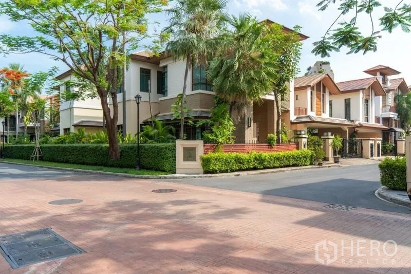独立式住宅 出租在Watthana, Bangkok - 高档社区街角外观，绿化环绕的现代别墅群。