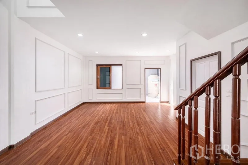 Townhouse for sale - Bright open-plan living area with wood floors, white panelled walls and a wooden staircase.