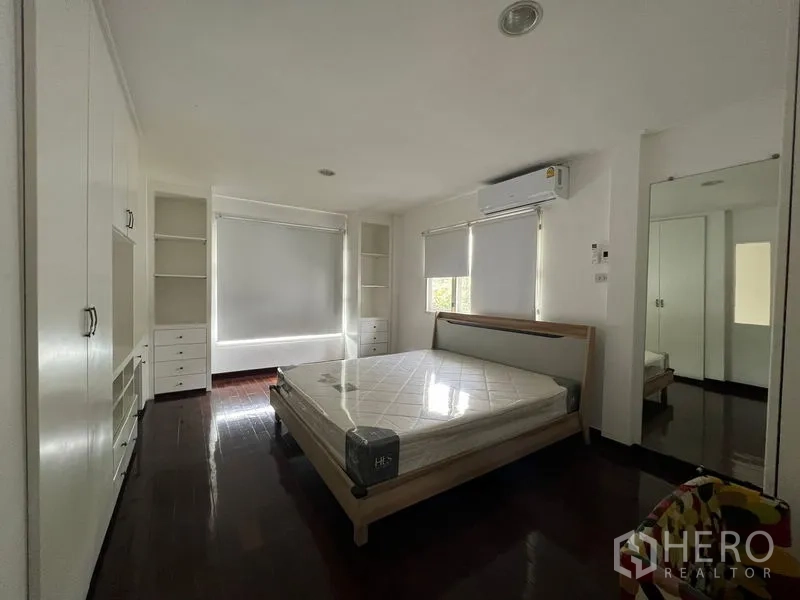 Detached House for rent in Saphan Sung, Bangkok - Lounge with L-shaped sofa, TV built-ins and staircase under a high ceiling.