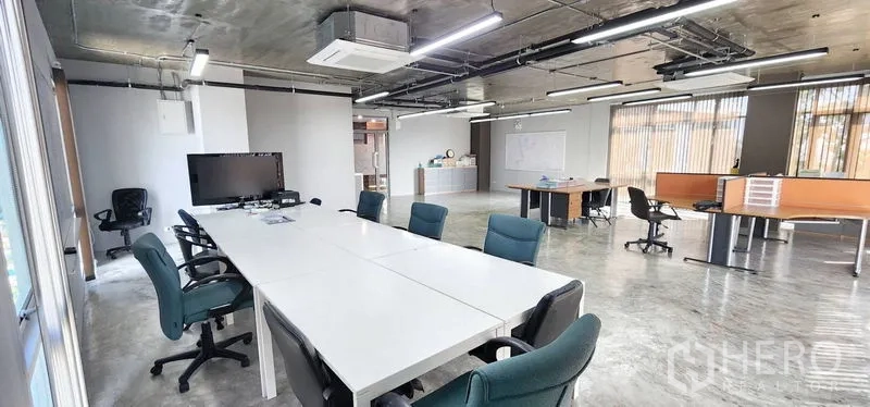 办公空间 出租 - 采光充足的办公区，长会议桌与办公椅，电视屏幕，工业风吊顶灯，窗边工作位。
