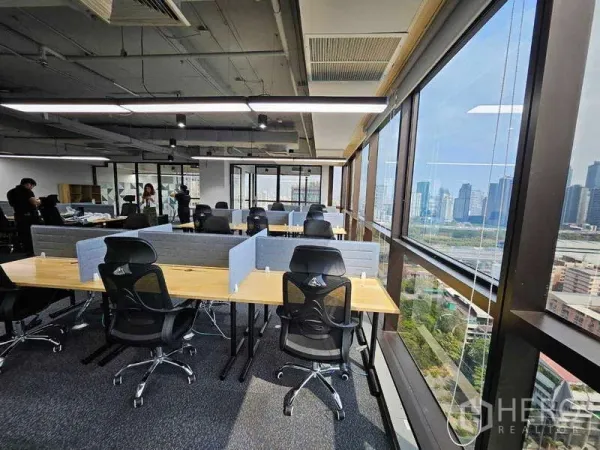 Office Space for rent in Ratchathewi, Bangkok - Row of ergonomic chairs at shared benches facing Bangkok skyline through wraparound windows.