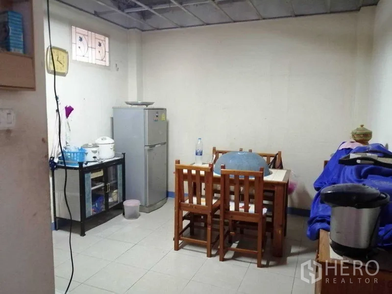 独立式住宅 出售在Prawet, Bangkok - 紧凑餐区，木桌、冰箱与置物架。