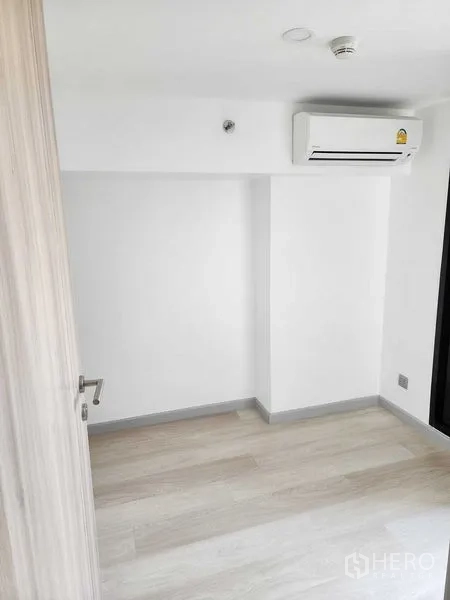 公寓 出售在Sathon, Bangkok - 白色墙面与浅色木地板的空卧室，配墙挂式空调。