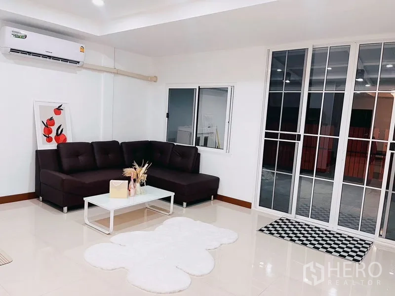 Townhouse for rent in Huai Khwang, Bangkok - Open living area with sliding glass doors, a window and wall-mounted air conditioner.