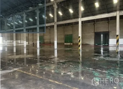 Warehouse for rent in Mueang Pathum Thani, Pathum Thani - Industrial interior showing polished concrete floor, structural columns, and safety-striped pillars.
