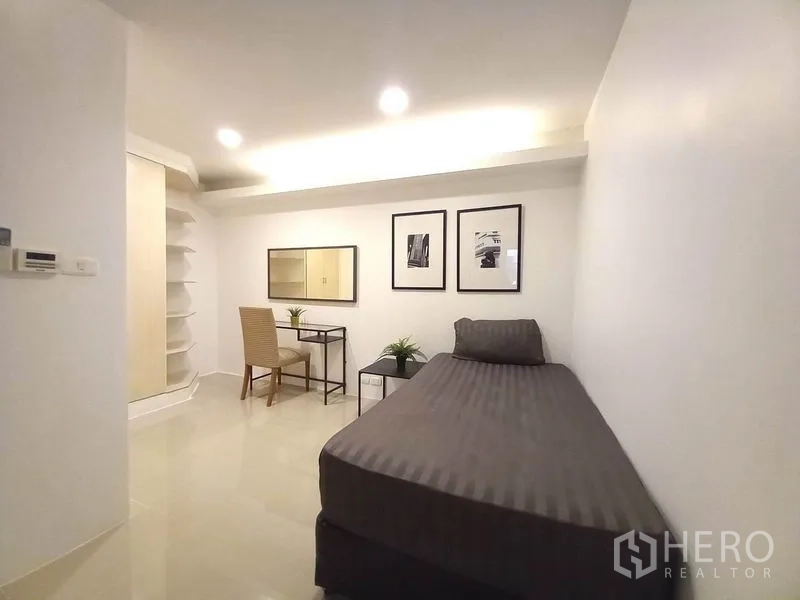 Condominium for rent in Khlong Toei, Bangkok - Cozy second bedroom with study corner and curved built-in shelving.