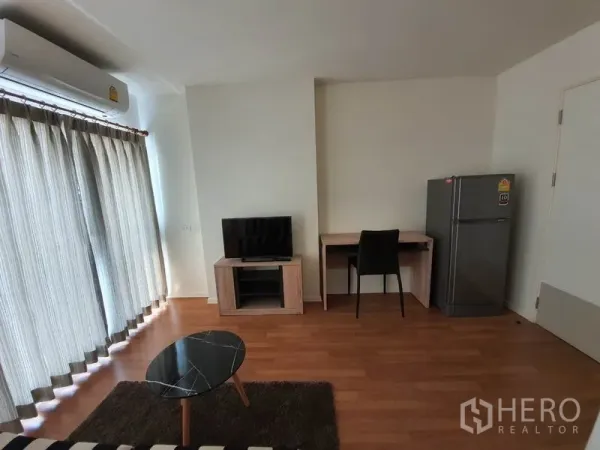 公寓 出售在Chatuchak, Bangkok - 起居区配阳台窗帘、电视柜、书桌和冰箱，曼谷公寓内部。