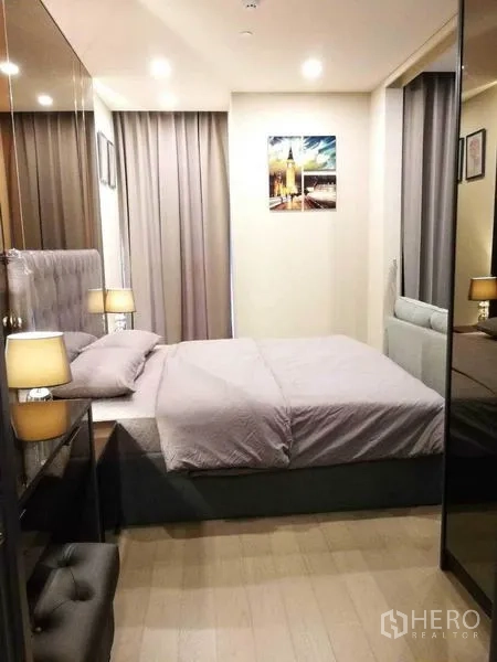 Condominium for rent in Watthana, Bangkok - Cozy bedroom with upholstered headboard, bedside lamps, mirrored wardrobe and soft curtains.